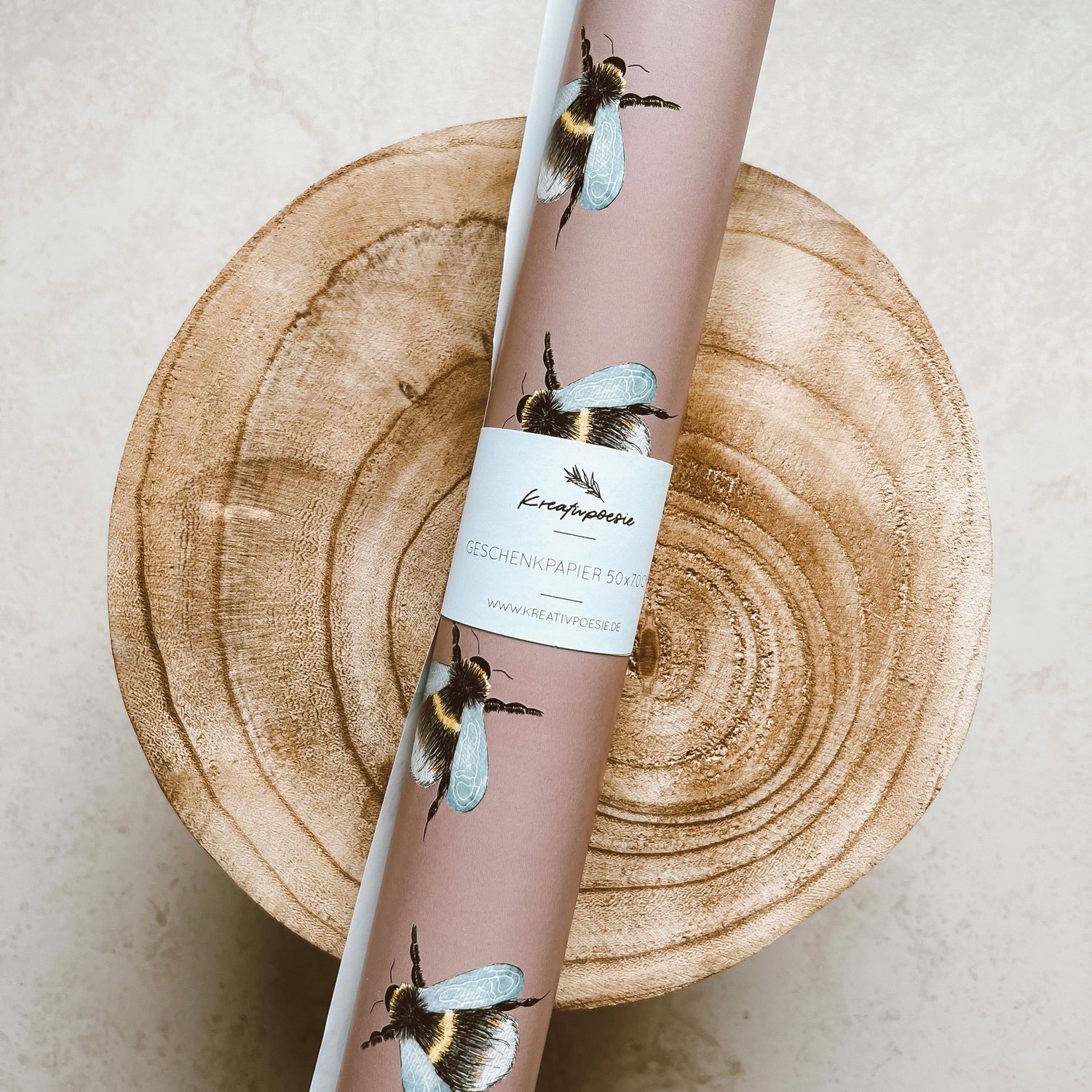 Geschenkpapier-Bogen in der Größe 50x70cm (aufgerollt). Der Hintergrund ist altrosa mit vielen Hummeln.