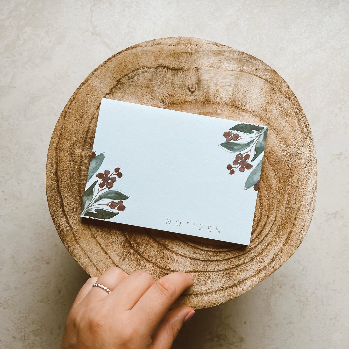 Notizblock DIN A6 mit grünen Pflanzenelementen in den Ecken. Text: ,,NOTIZEN''.