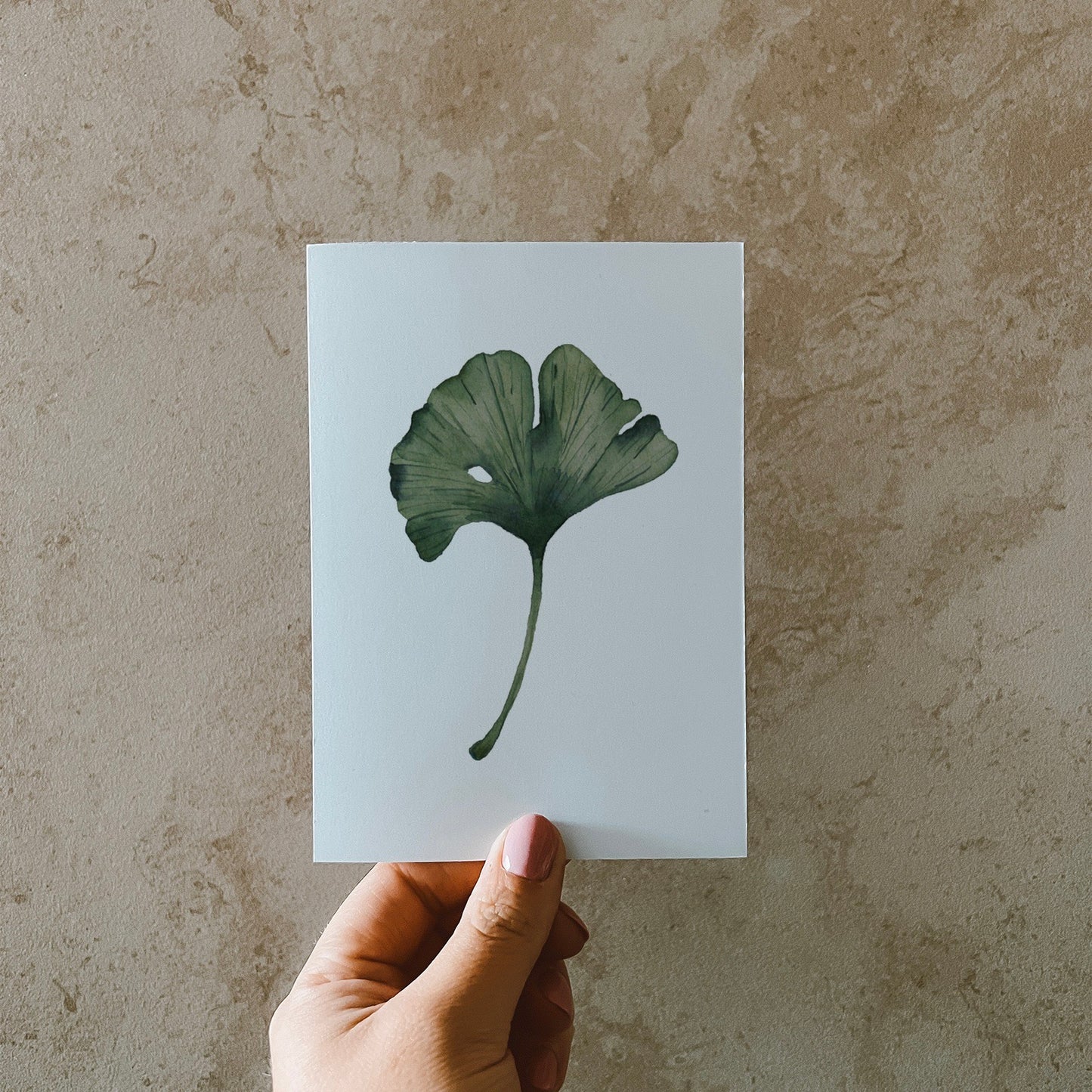 Postkarte DIN A6, Recyclingpapier, gedruckt in Deutschland. Auf dieser Karte befindet sich mittig ein grünes Ginkgoblatt, welches mit Aquarellfarben illustriert wurde.