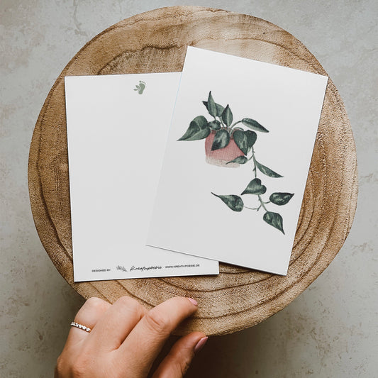 Herunterhängende Efeutute im rosa-beigen Blumentopf.