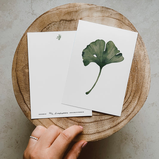 Postkarte DIN A6, Recyclingpapier, gedruckt in Deutschland. Auf dieser Karte befindet sich mittig ein grünes Ginkgoblatt, welches mit Aquarellfarben illustriert wurde.
