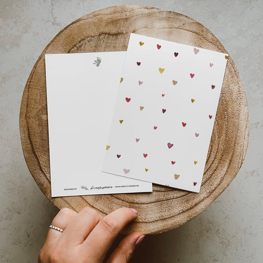 Postkarte DIN A6 im Hochformat. Auf dieser Karte befinden sich verschiedene kleine Herzen in bunten Farben.