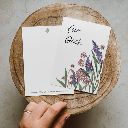 Postkarte DIN A6, Hochformat, gedruckt in Deutschland. Auf diese Karte befinden sich unten rechts in der Ecke eine Aquarellillustration, auf der verschiedene Wildblumen zu erkennen sind. Oben links in der Ecke befindet sich ein Lettering ,,für dich''.