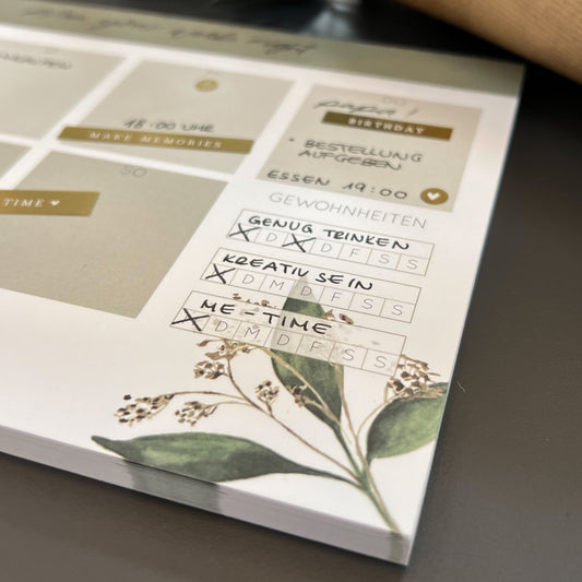 Notizblock DIN A5 Wochenplaner, quer mit mit grünen Pflanzenelementen in de Ecke. Lettering: ,,plan your week right''.
