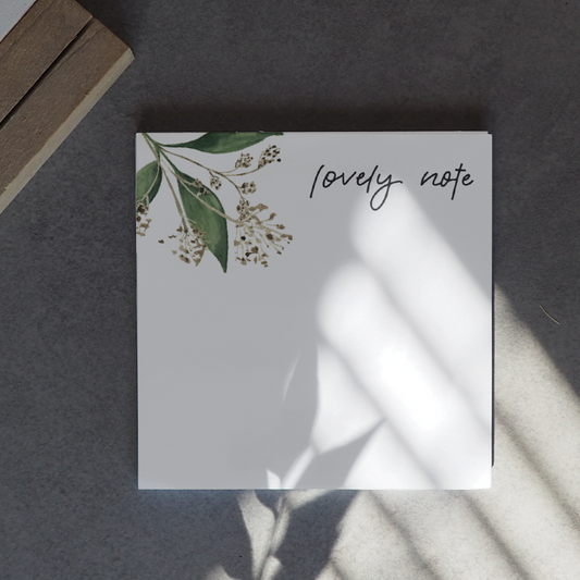 Notizblock 90x90mm mit grünen Pflanzenelementen in de Ecke. Lettering: ,,lovely note''.