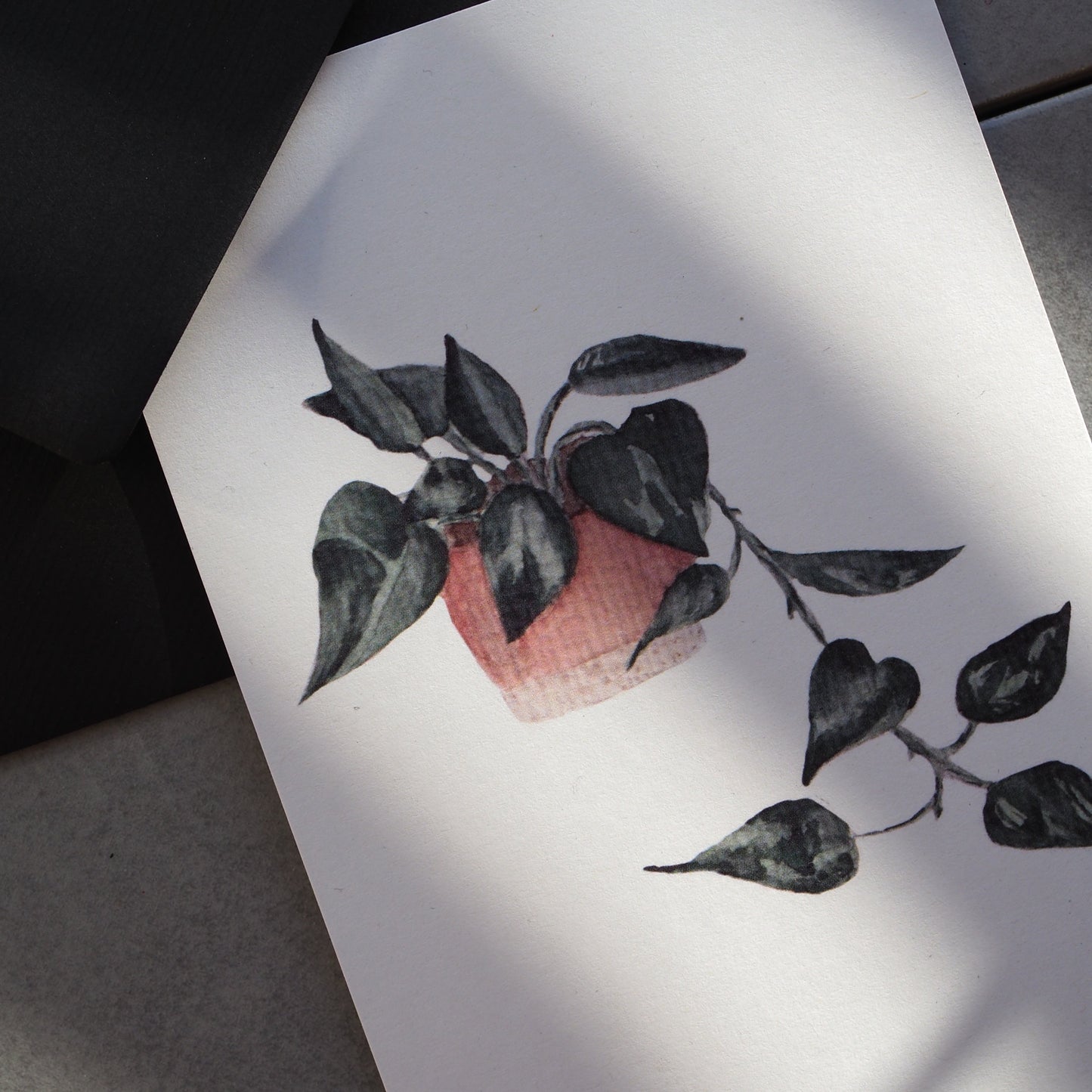 Herunterhängende Efeutute im rosa-beigen Blumentopf.