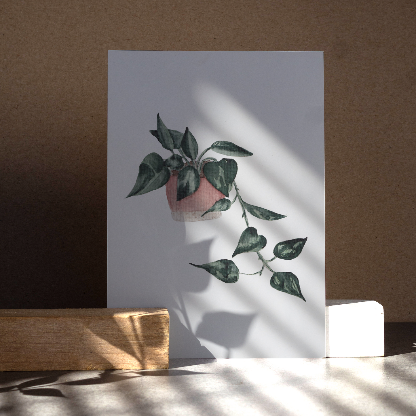 Herunterhängende Efeutute im rosa-beigen Blumentopf.
