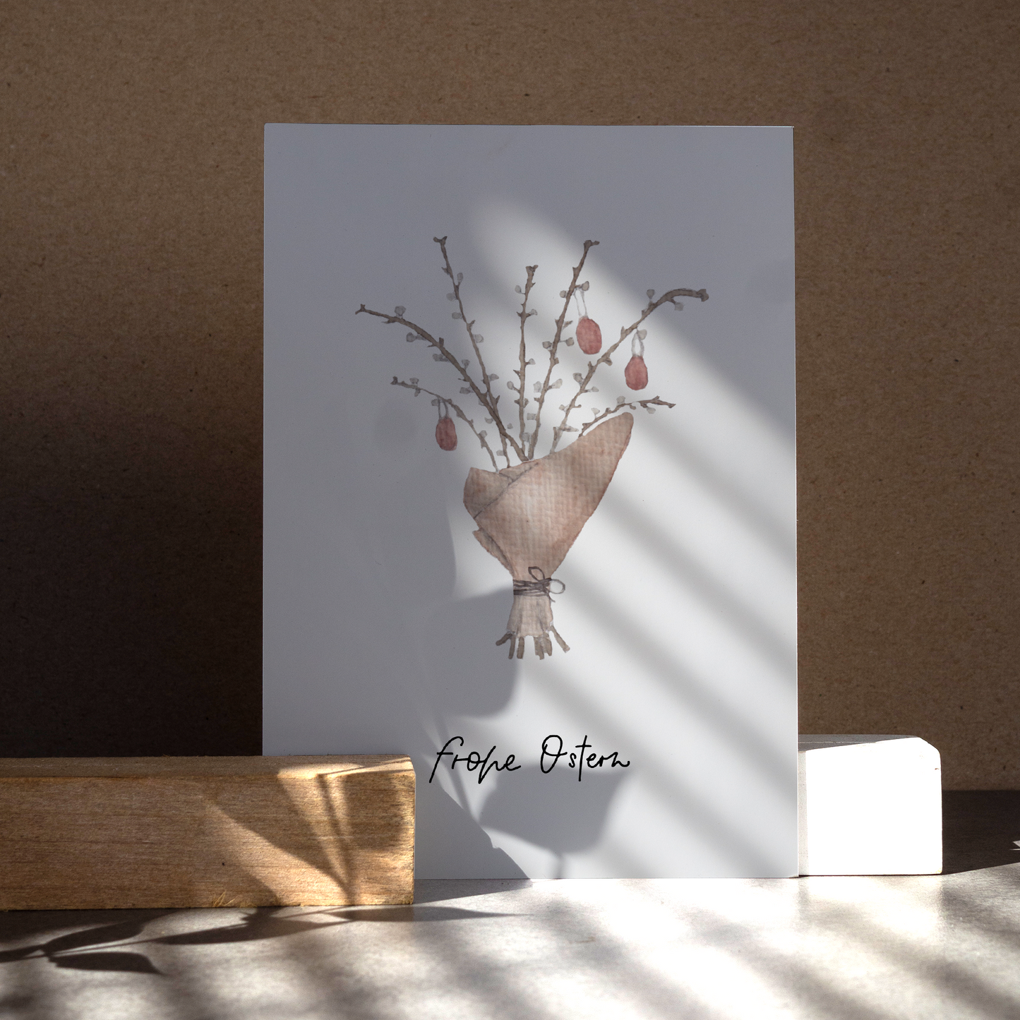 Aquarellierte Osterstrauch, eingewickelt in braunem Papier mit roten Eiern. Text: ,,frohe Ostern''.