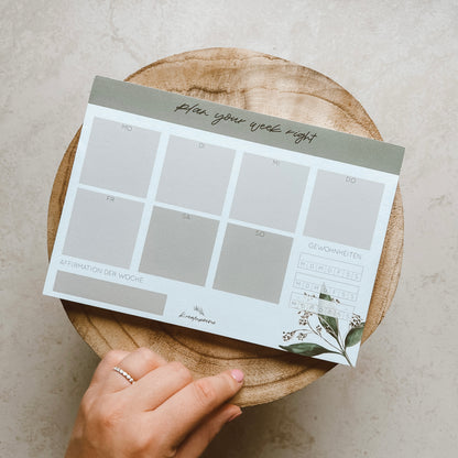 Notizblock DIN A5 Wochenplaner, quer mit mit grünen Pflanzenelementen in de Ecke. Lettering: ,,plan your week right''.