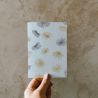Postkarte DIN A6 im Hochformat. Vielen Gänseblümchen im Line-Art-Stil und Aquarellstil.