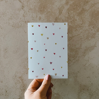 Postkarte DIN A6 im Hochformat. Auf dieser Karte befinden sich verschiedene kleine Herzen in bunten Farben.