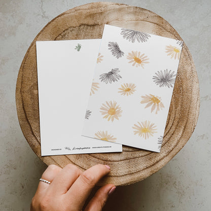Postkarte DIN A6 im Hochformat. Vielen Gänseblümchen im Line-Art-Stil und Aquarellstil.